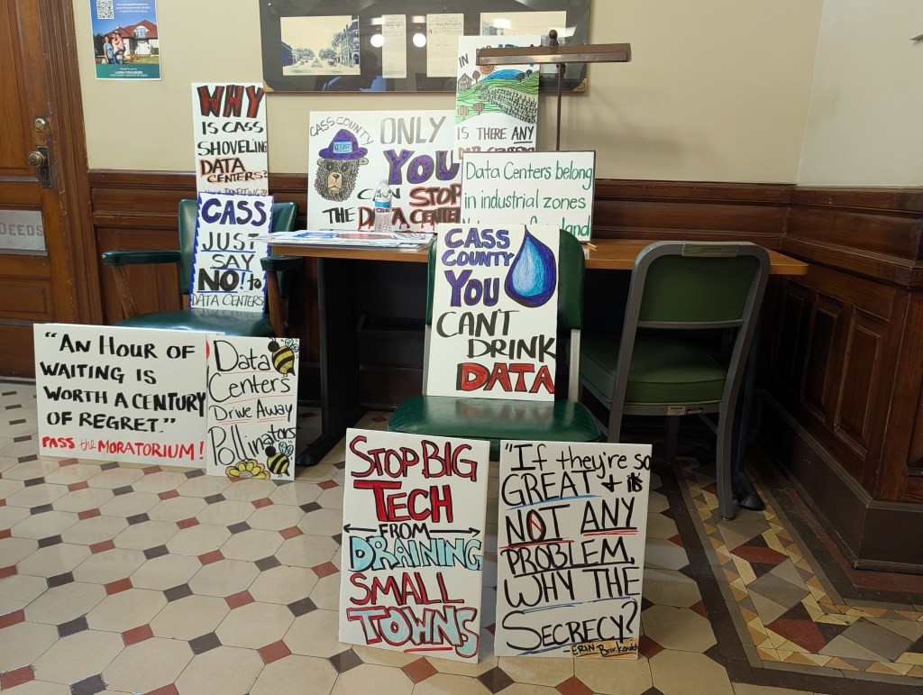 Signs protesting data centers in Cass County, Nebraska, line the wall outside of the board of commissioner's hearing room on Tuesday, Aug. 11, 2026. | Photo: Chase Porter/Courier Nebraska