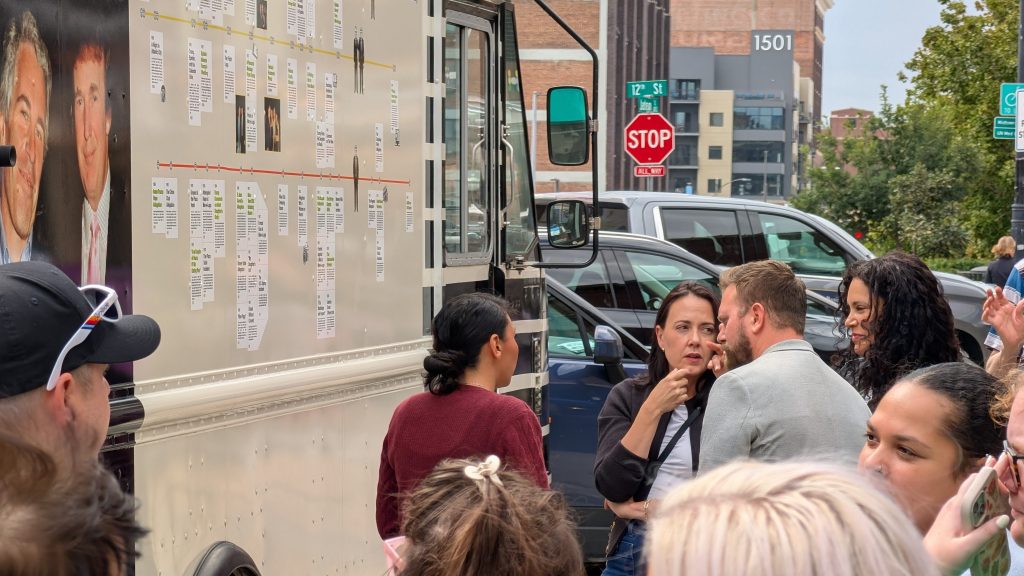 Denise Powell, Democratic nominee for Nebraska's 2nd congressional district, listens to survivors of the Jeffrey Epstein's sex trafficking operation while she tours the "Donald J. Trump and Jeffrey Epstein Memorial Bookmobile" during its stop in Omaha, Nebraska, on Monday, Sept. 14, 2026. | Photo: Chase Porter/Courier Nebraska