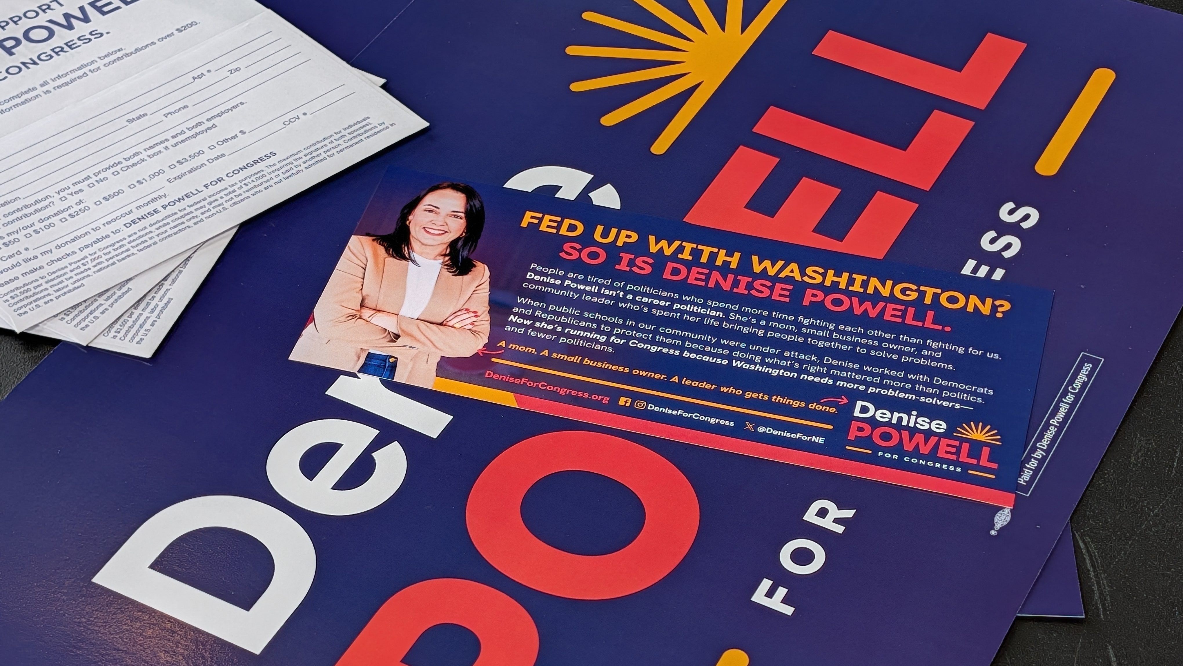 Campaign postcards and signs for Denise Powell, Democratic nominee in Nebraska’s 2nd Congressional District, sit clustered on a table ahead of an Omaha town hall with the candidate. | Photo by Chase Porter/Courier Nebraska